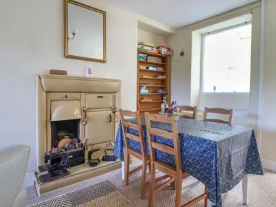 a dining room with a table and a fireplace at Glasfryn in Dolgellau