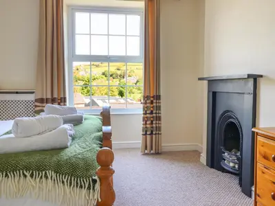 a bedroom with a bed with a fireplace and a window at Glasfryn in Dolgellau
