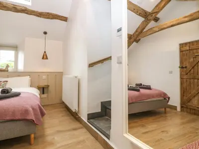 a bedroom with two beds and a mirror at Y Stabl in Dyffryn