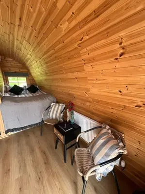 a room with a bed and chairs in a log cabin at The Pod Patch - Bryn Pod in Bishops Castle