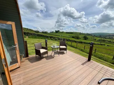 a wooden deck with two chairs and a table at The Pod Patch - Bryn Pod in Bishops Castle