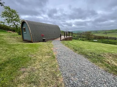 a small building with a roof on a grass field at The Pod Patch - Bryn Pod in Bishops Castle