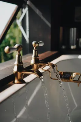 a brass bathroom faucet with water coming out of it at Two unique cabins wrapped in beautiful welsh scenery in Presteigne