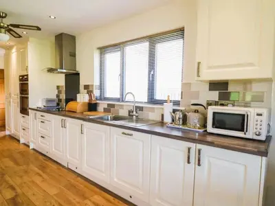a kitchen with white cabinets and a microwave at Caban Dulas in Nantmel
