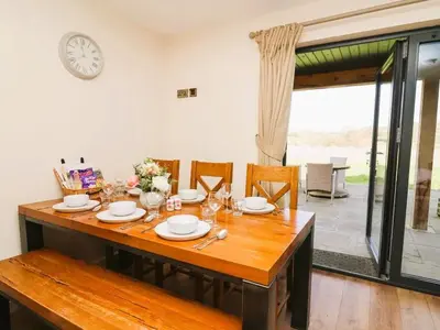 a dining room table with chairs and a clock on the wall at Caban Dulas in Nantmel