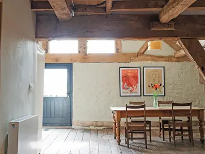 a dining room with a wooden table and chairs at Hayloft Barn in Clifford