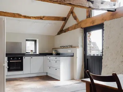 a kitchen with white cabinets and a black counter top at Hayloft Barn in Clifford