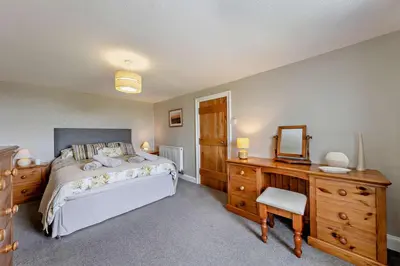 a bedroom with a bed and a dresser and a mirror at 3 Bed in Dyffryn Ardudwy oc-f29350 in Dyffryn