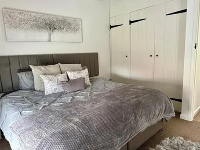 a bedroom with a large bed and white cabinets at Serafina Cottage in Leominster
