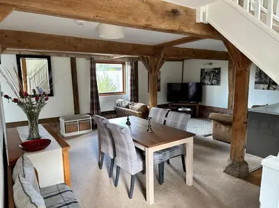a living room with a wooden table and chairs at Serafina Cottage in Leominster