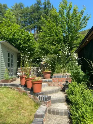 a garden with potted plants on a brick path at The chapel in Machynlleth