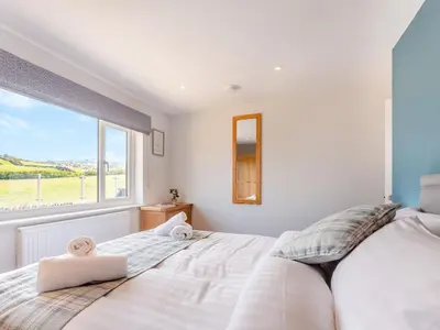 a bedroom with a large white bed and a window at Goppa in Llanfair