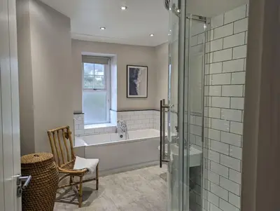 a bathroom with a tub and a glass shower at Pencartref Apartment - 4 Bedrooms, 3 Bathrooms, Sleeps 7-8 in Aberdyfi
