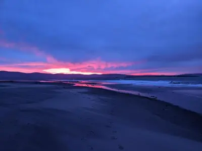a sunset over a beach with footprints in the sand at Pencartref Apartment - 4 Bedrooms, 3 Bathrooms, Sleeps 7-8 in Aberdyfi