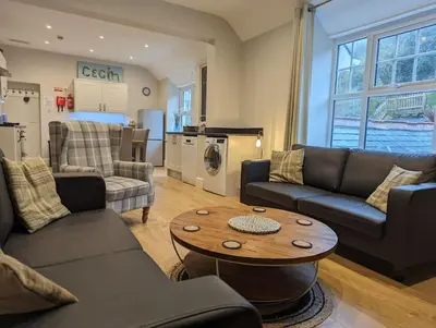a living room with couches and a table and a kitchen at Pencartref Apartment - 4 Bedrooms, 3 Bathrooms, Sleeps 7-8 in Aberdyfi