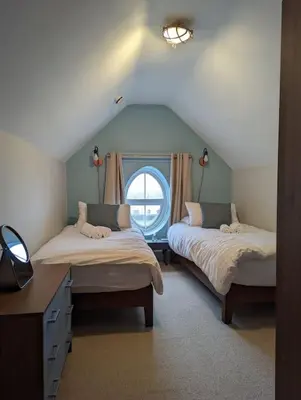 a attic room with two beds and a window at Pencartref Apartment - 4 Bedrooms, 3 Bathrooms, Sleeps 7-8 in Aberdyfi
