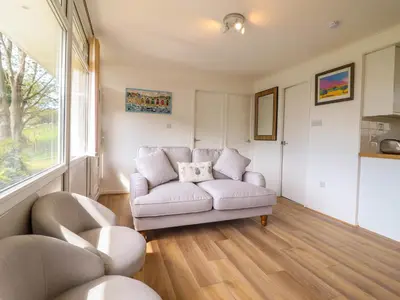 a living room with a white couch and a window at Hill View in Tywyn