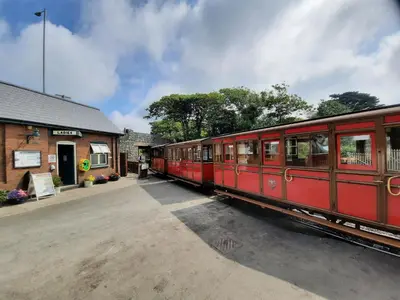 a red train is parked at a train station at Hill View in Tywyn