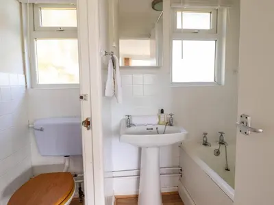a white bathroom with a sink and a bath tub at Hill View in Tywyn