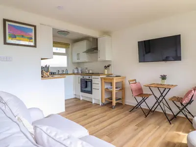 a living room with a couch and a kitchen at Hill View in Tywyn