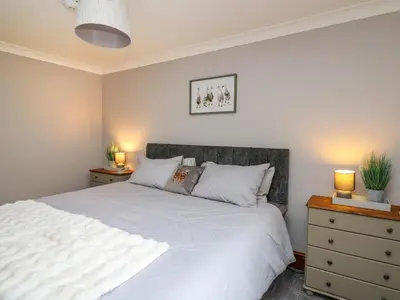 a bedroom with a white bed and two night stands at Pondarosa in Llandrindod Wells