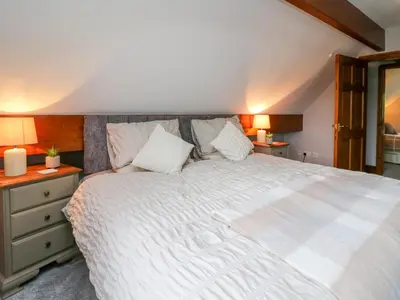 a bedroom with a large white bed with two lamps at Pondarosa in Llandrindod Wells