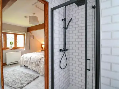 a glass shower door in a bedroom with a bed at Pondarosa in Llandrindod Wells