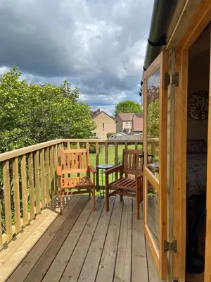 a wooden deck with two chairs and a table at Stylish Shepherds Hut with Amazing Views in Knighton