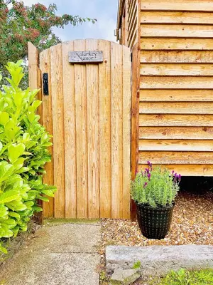 a wooden fence with a sign on it and a pot of flowers at Stylish Shepherds Hut with Amazing Views in Knighton