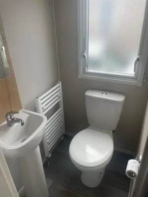 a bathroom with a white toilet and a sink at Caravan by the beach in Borth