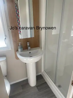 a bathroom with a white sink and a shower at Caravan by the beach in Borth