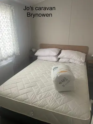 a white bed with a pillow on top of it at Caravan by the beach in Borth