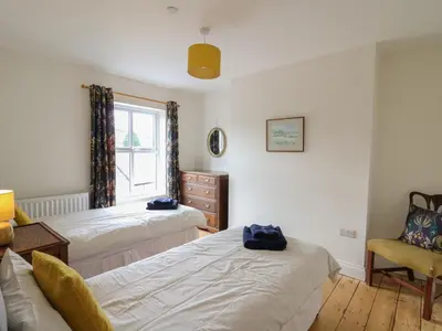 a bedroom with two beds and a chair and a window at Osborne House in Rhayader
