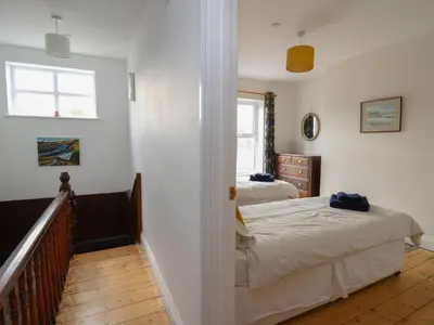 a bedroom with two beds and a window and a staircase at Osborne House in Rhayader