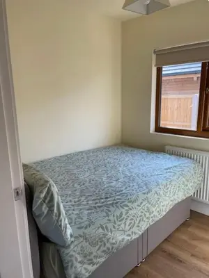 a bedroom with a bed with a blue comforter and a window at Weston pools Lodge with 6 Bedrooms in Oswestry