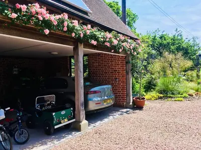 a garage with cars parked next to a brick building with flowers at The Guest House near Hay on Wye in Hereford