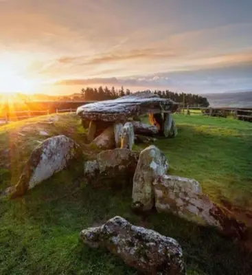 a stone bench in a field with the sunset in the background at The Guest House near Hay on Wye in Hereford