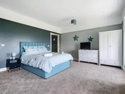a bedroom with a blue bed and a tv at Plas Amherst in Harlech