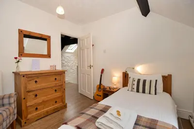 a bedroom with a bed and a dresser and a guitar at Finest Retreats - Hermon Bach in Dolgellau