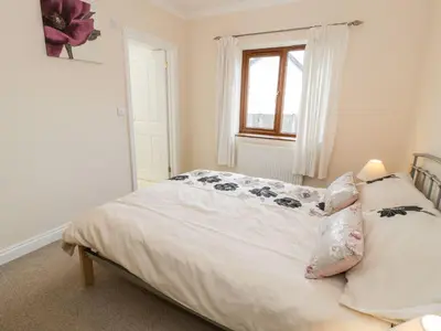 a bedroom with a bed with white sheets and a window at Tremyfron in Bala
