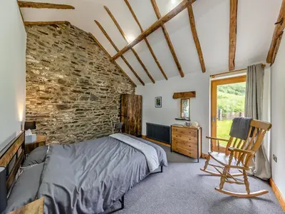 a bedroom with a bed and a brick wall at Ty Carreg in Llanbadarn-fawr