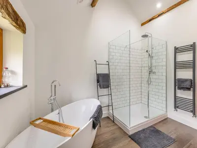 a white bathroom with a tub and a glass shower at Ty Carreg in Llanbadarn-fawr
