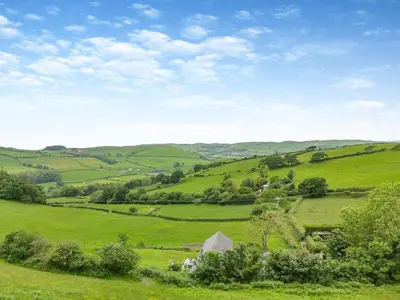 a green hillside with a farm in the middle at Ty Carreg in Llanbadarn-fawr