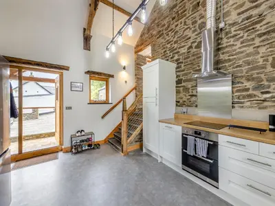 a kitchen with white cabinets and a stone wall at Ty Carreg in Llanbadarn-fawr