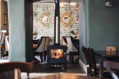 a fireplace in a dining room with chairs and a table at White Lion Royal Hotel in Bala