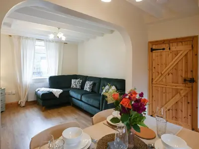 a living room with a couch and a table with flowers at Llys Dedwydd in Dolgellau