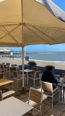 a man sitting at a table under an umbrella at the beach at Discover Serenity in Our 3-Bed Static Caravan at Clarach Bay Holiday Village! in Aberystwyth
