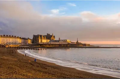 a view of a beach with a pier and the ocean at Discover Serenity in Our 3-Bed Static Caravan at Clarach Bay Holiday Village! in Aberystwyth