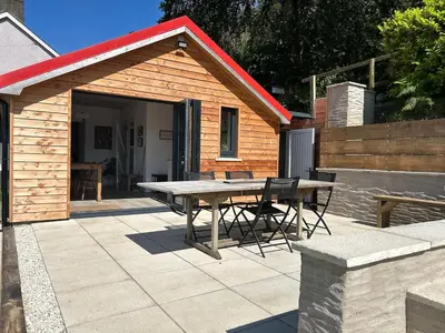a patio with a table and chairs in front of a shed at The Bw thyn - Ceredigion in Lampeter