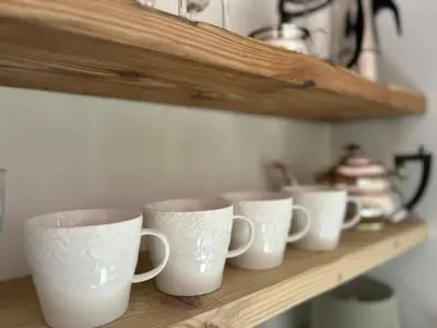 a row of white coffee cups sitting on a shelf at The Bw thyn - Ceredigion in Lampeter